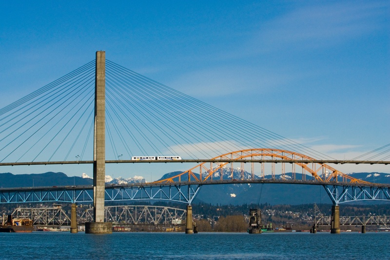 The Fraser river with bridges and Rocky Mountains in the distance