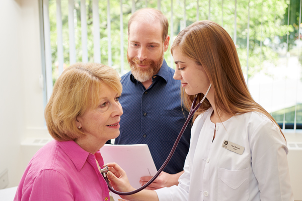 A male naturopathic doctor supervises a female intern with a female patient